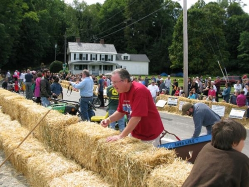 piles of hay bales line a soapbox race track with people on and off the track